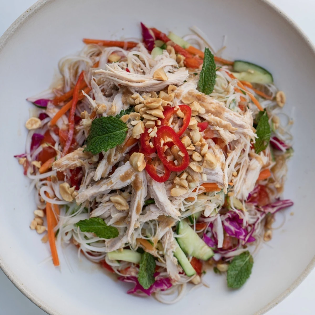 Heaping bowl of vibrant Vietnamese Crunch Noodle Salad with shredded chicken, a refreshing meal.