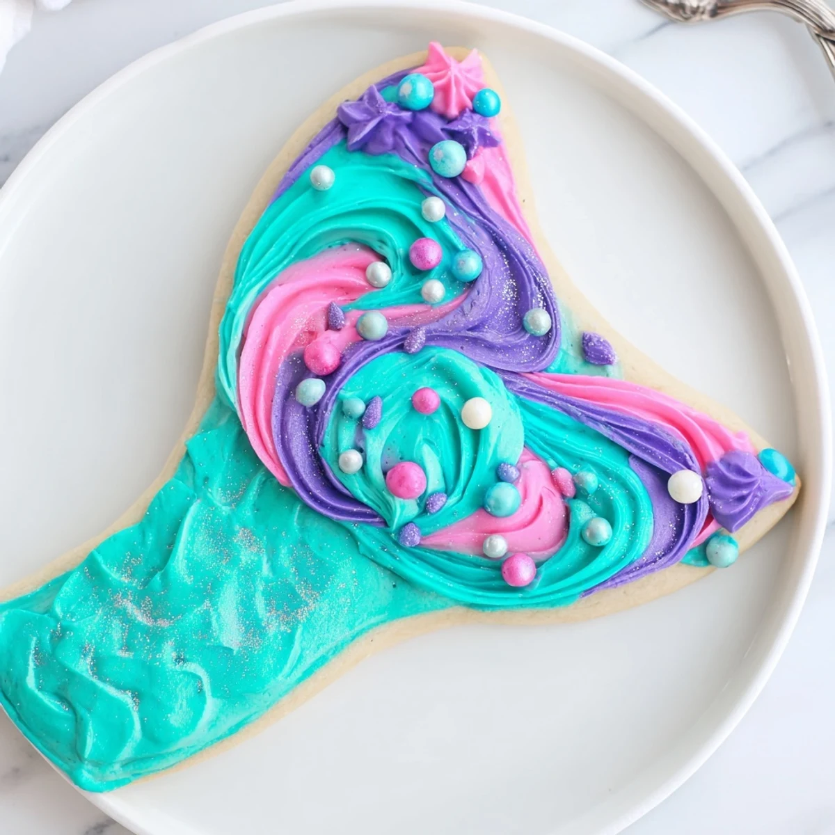 Shimmering Mermaid Tail Under the Sea Sweets feature colorful buttercream and edible shimmer, a festive dessert.