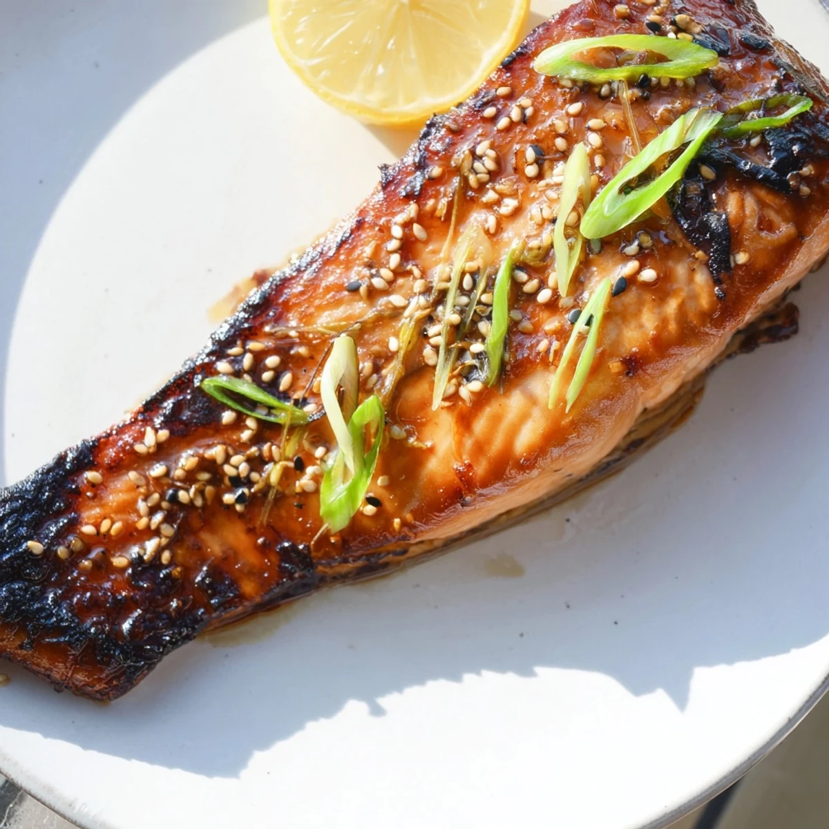 Flaky, pan-seared Ginger Soy Glazed Salmon with a dark, glossy glaze, garnished simply with green onions.