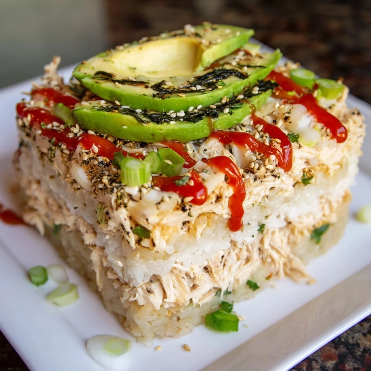 Warm and creamy chicken sushi bake with a topping of avocado and sesame seeds, ready to eat.