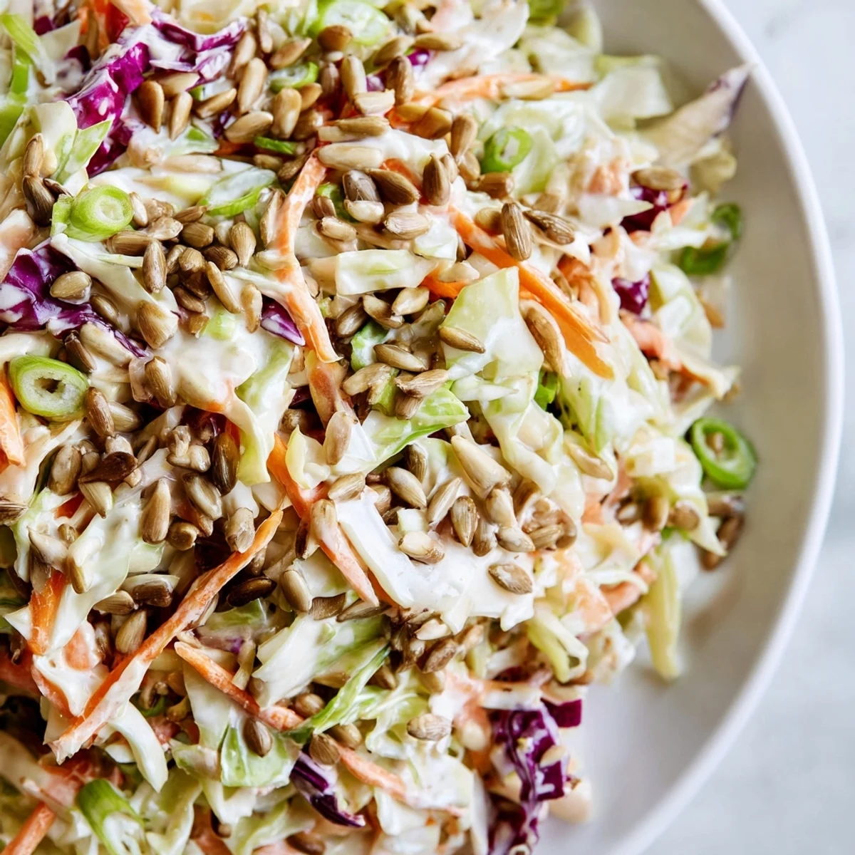 Crisp Crunchy Coleslaw Salad, with a creamy dressing, and garnished with sunflower seeds on top.