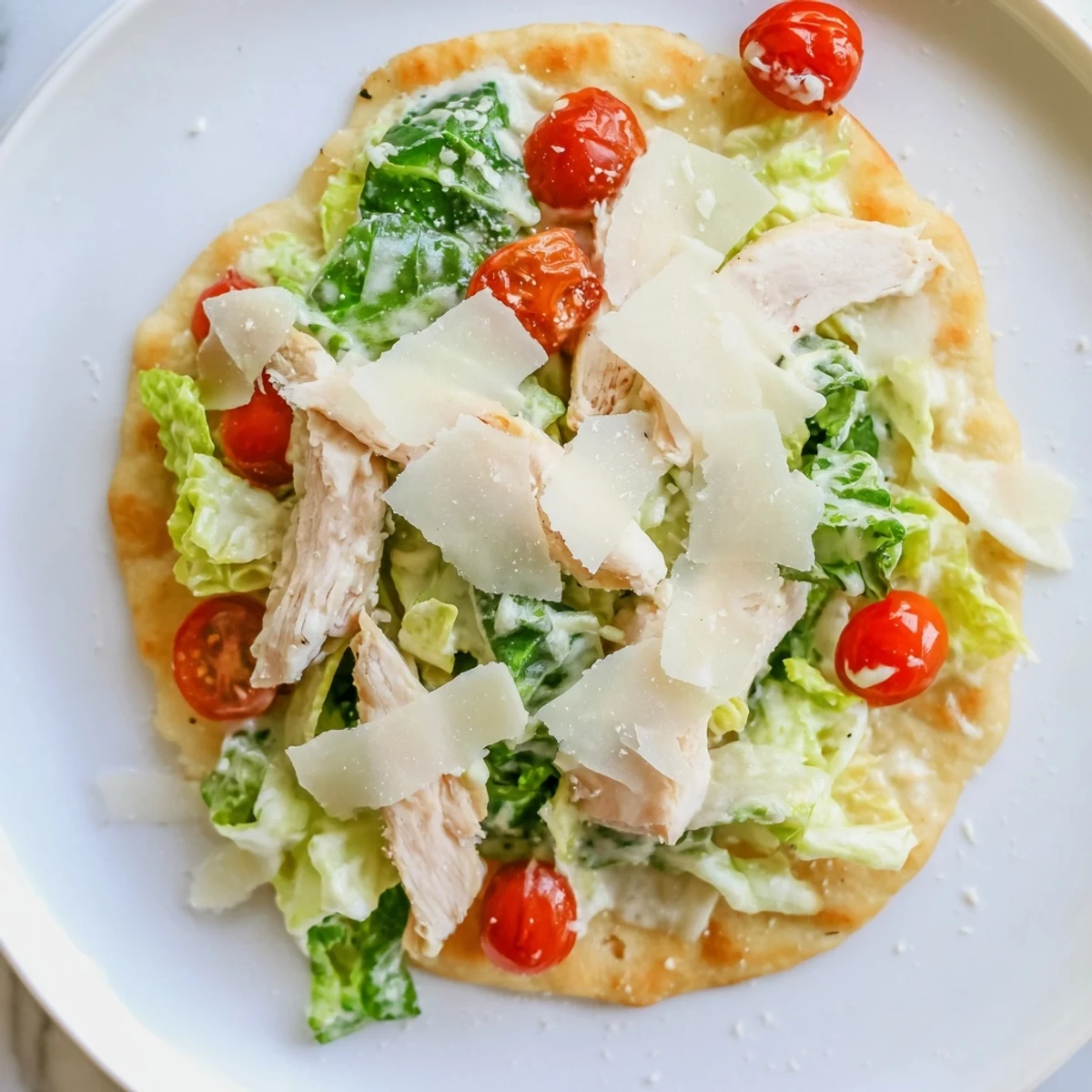 A close-up of Caesar Chicken Flatbread, featuring golden, crispy crust topped with grilled chicken slices, fresh romaine, Parmesan shavings, and creamy Caesar dressing.