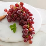 Sweet, juicy grapes spilling from a wooden board, ready for a refreshing snack.