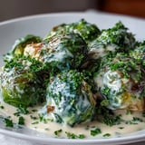 Tender Brussels sprouts in a rich Dijon mustard and cream cheese sauce, ready to serve as a savory vegetarian dinner.