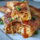 Golden-brown Buffalo Chicken Dip Egg Rolls on a platter, filled with creamy, spicy chicken and melty cheddar, served with ranch.