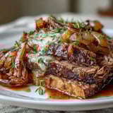 Slow-cooked Savory Crock Pot French Onion Pot Roast in a crock pot with onions and thyme.
