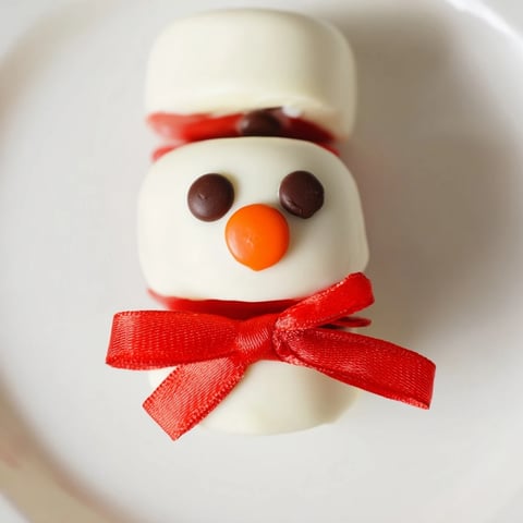 Express Snowman Marshmallow Pops, dipped in white chocolate, ready for a winter treat alongside hot cocoa.