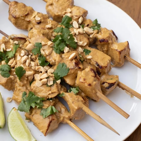 Grilled Spicy Peanut Satay Chicken Skewers, charred and glistening, served with fresh cilantro.
