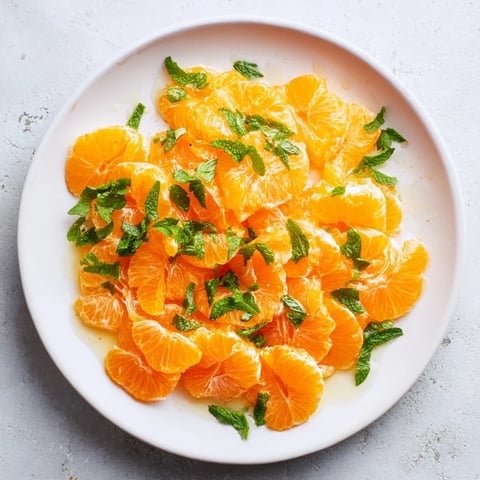 Bright clementine and mint winter fruit salad, a colorful and zesty holiday dessert, ready to enjoy.