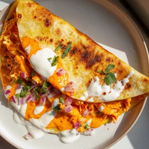 Golden-brown Buffalo Chicken Quesadilla, oozing melted cheese and filling your kitchen with savory aromas.