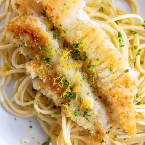 Flaky golden fish and bright lemon zest tossed with al dente spaghetti in a skillet for a vibrant Mediterranean dinner.