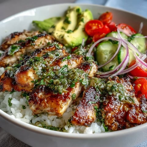 Grilled chimichurri chicken bowl with fluffy rice, avocado slices, and fresh cherry tomatoes.