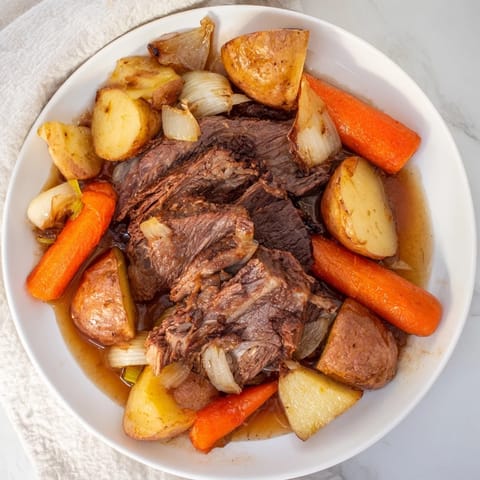 Fork-tender Sunday Pot Roast, surrounded by roasted carrots and potatoes, ready to be devoured.