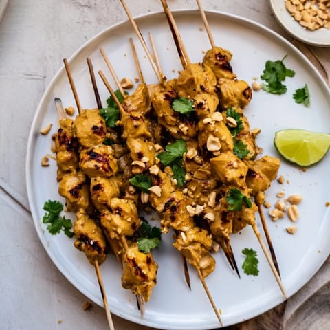 Juicy Spicy Peanut Satay Chicken Skewers, perfectly grilled and ready to be enjoyed with lime wedges.