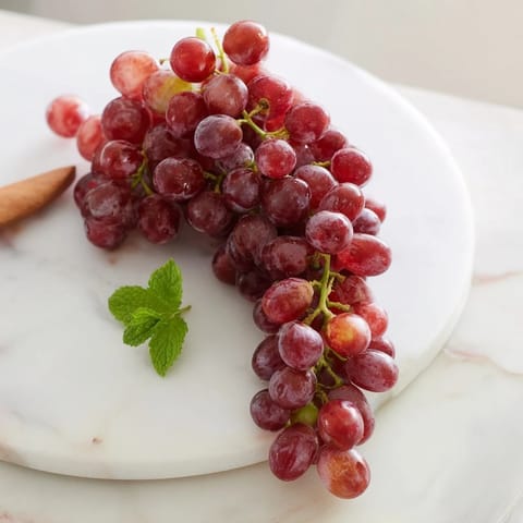 Sweet, juicy grapes spilling from a wooden board, ready for a refreshing snack.