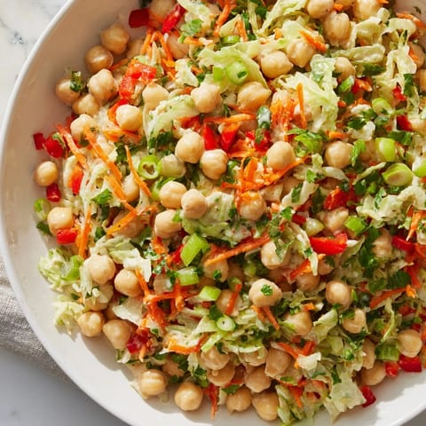 A fresh, colorful photo of fiber-forward chickpea salad topped with green onions and parsley.