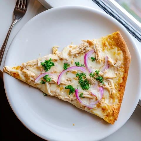 Freshly baked Chicken Alfredo Pizza topped with tender chicken, Parmesan, and chopped parsley garnish.