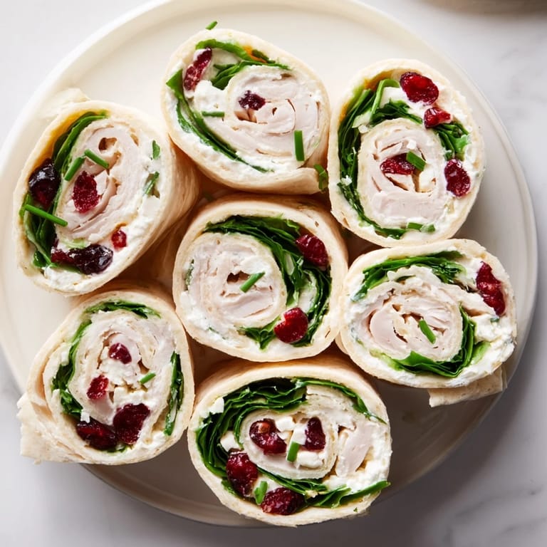 Freshly sliced Simplified Turkey Cranberry Pinwheels revealing a creamy, cranberry-filled interior with hints of spinach.