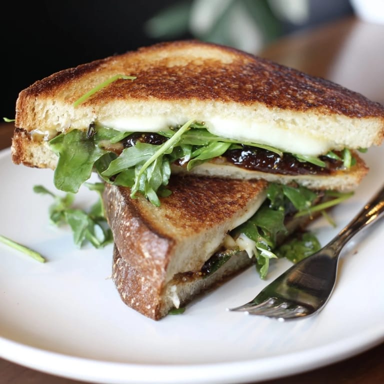 Crispy sourdough with melted Brie and fig jam: a gourmet Fig, Brie & Arugula Grilled Cheese sandwich.