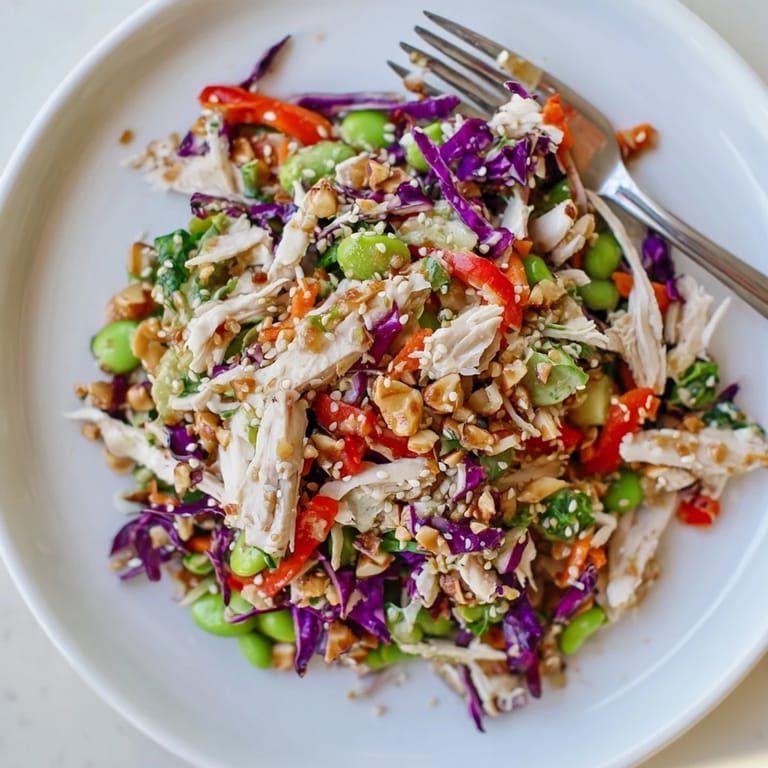 Serving suggestion for Edamame Crunch Chicken Salad in a glass bowl, with lime wedges and a fork, perfect for a light, high-protein lunch.