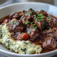 A bowl of lightened Irish beef stew with tender beef and vegetables, served over creamy cauliflower mash.  