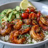 A vibrant bowl of easy healthy lemon garlic shrimp served over brown rice with fresh vegetables and avocado.
