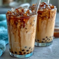 Rich brown sugar boba milk tea with chewy tapioca pearls and a sweet syrup drizzle in a clear glass.